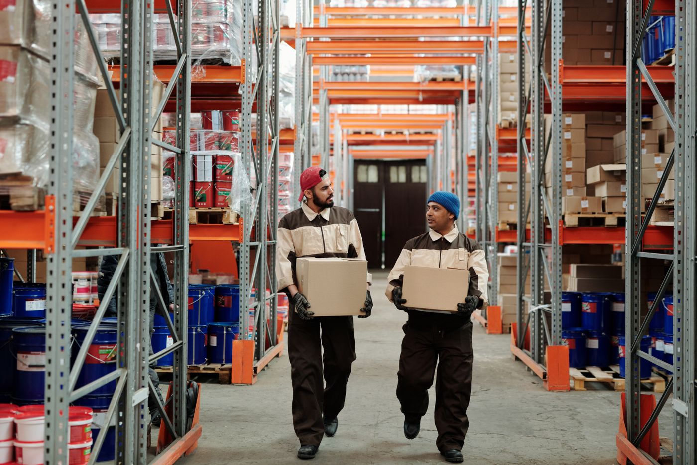 Warehouse workers carrying shipping boxes through a cargo storage aisle